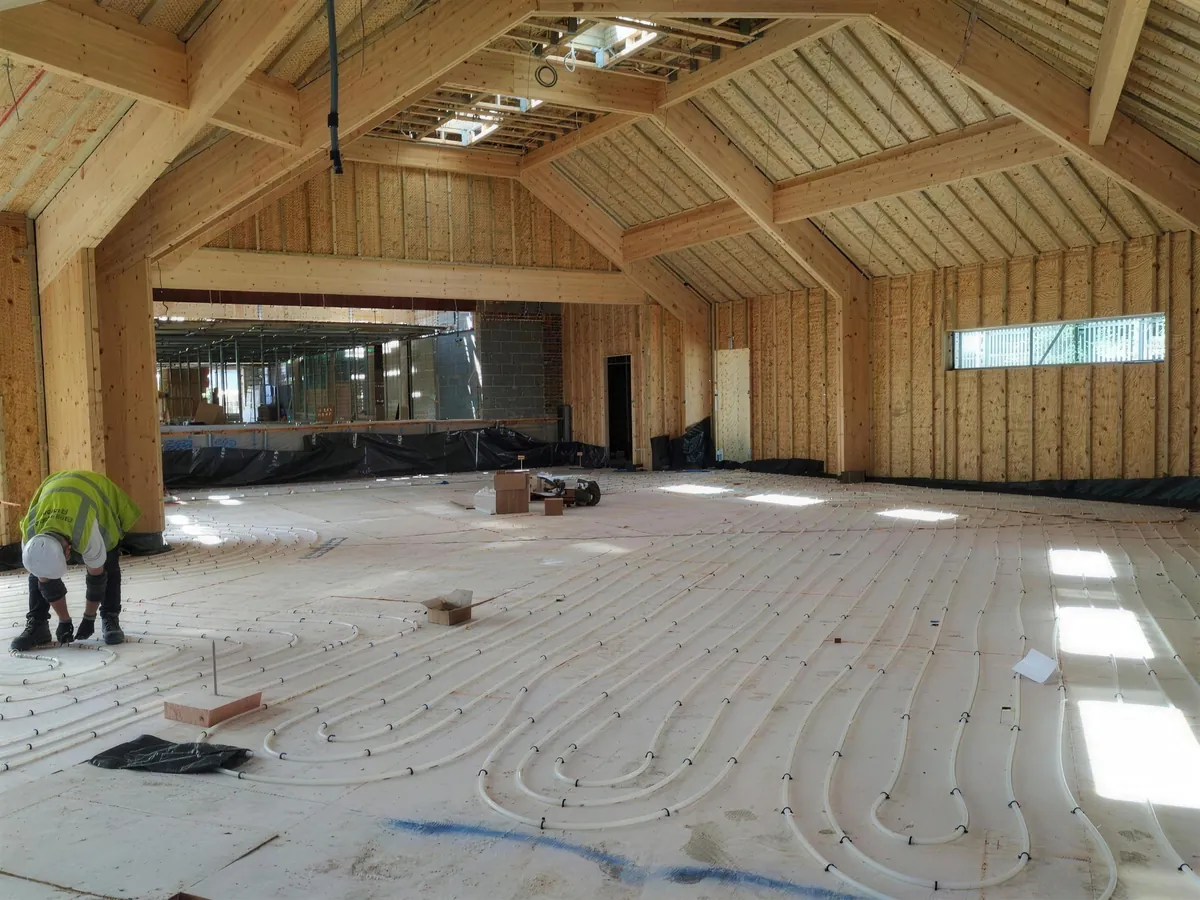 Underfloor heating pipes laid across the Link Barn floor under the timber-lined roof