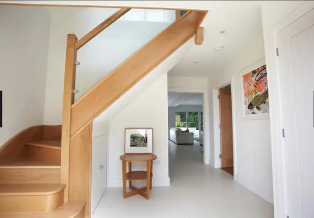Hallway with an oak and glass staircase and pale tiled floor