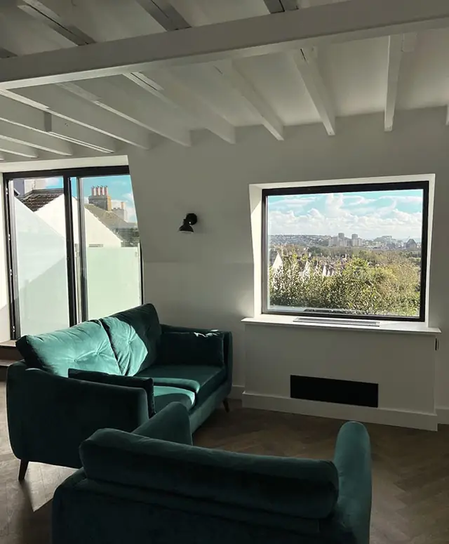 Living room with green velvet sofas and a large window