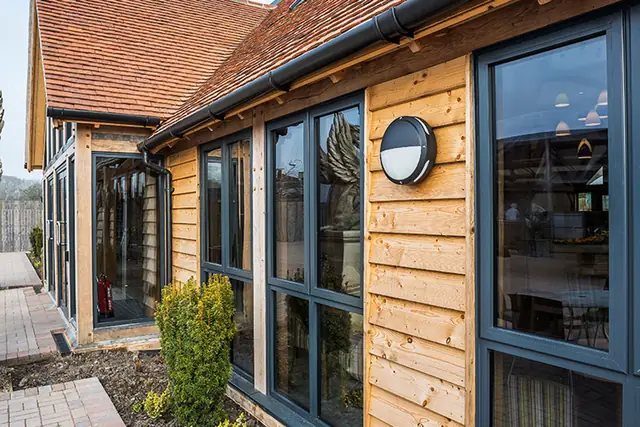 Timber clad exterior with grey framed windows and a clay tiled roof