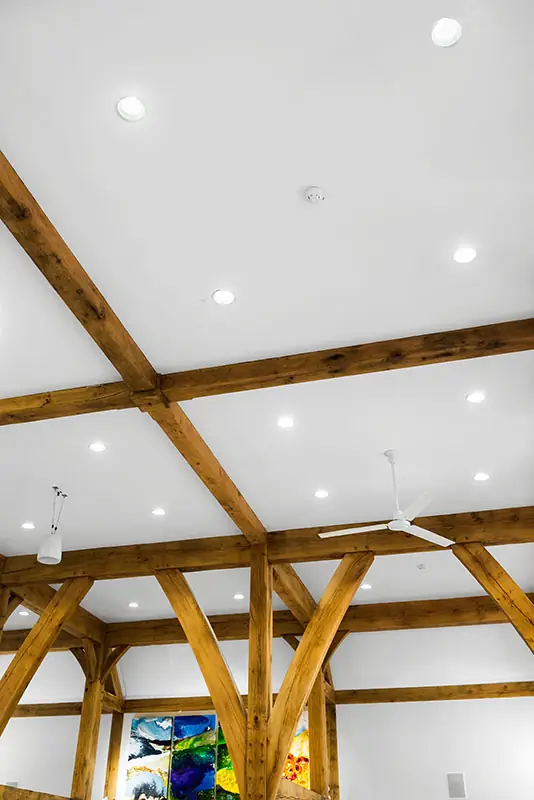 Oak trusses and recessed lights across the white ceiling