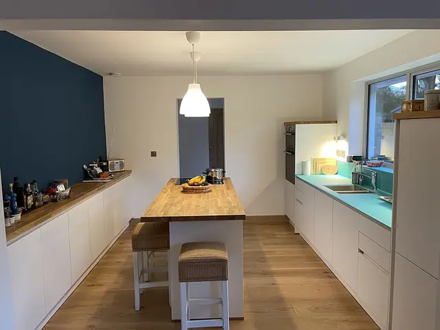 Kitchen with an island, pendant light and a blue feature wall