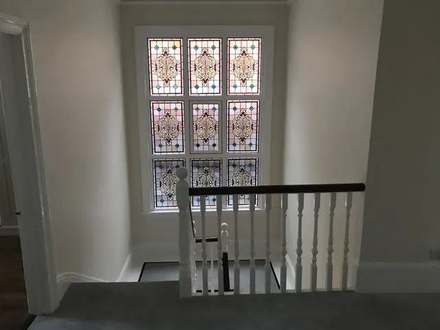 Staircase landing with a restored stained glass window